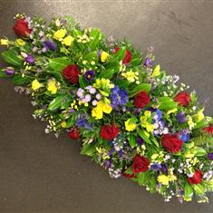 Casket spray in reds, yellows and purples